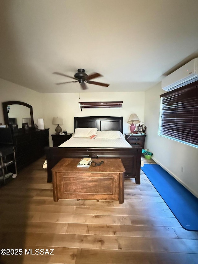 bedroom with hardwood / wood-style floors, a wall mounted AC, and ceiling fan