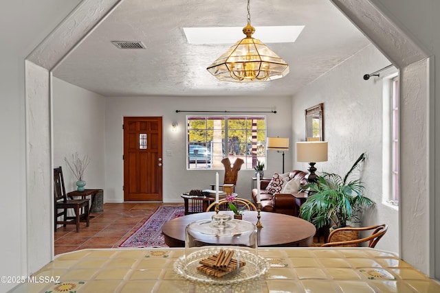 tiled dining space featuring a skylight and a textured ceiling