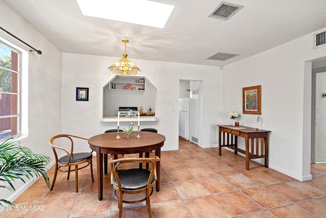 tiled dining room featuring a skylight