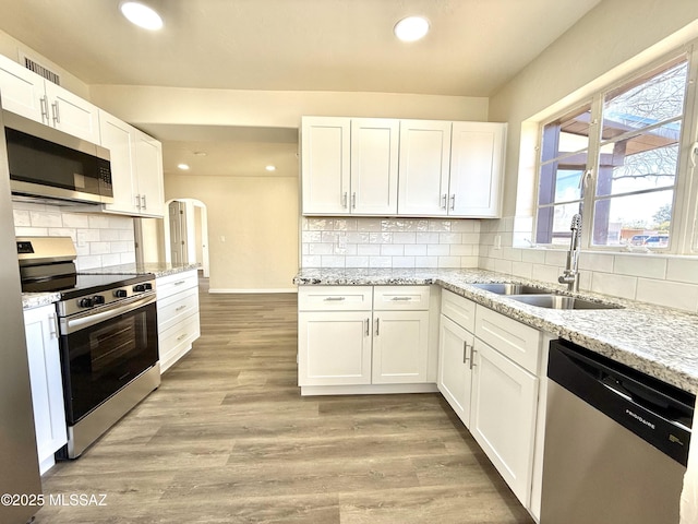 kitchen with white cabinetry, appliances with stainless steel finishes, sink, and light hardwood / wood-style flooring