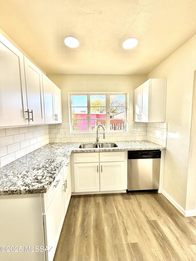 kitchen with white cabinetry, sink, light stone counters, and dishwasher