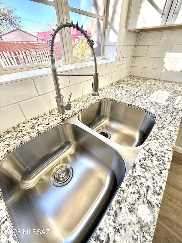 interior details with sink, decorative backsplash, and light stone countertops