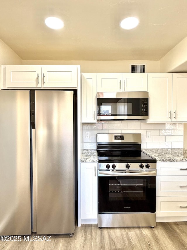 kitchen featuring appliances with stainless steel finishes, light stone countertops, and white cabinets