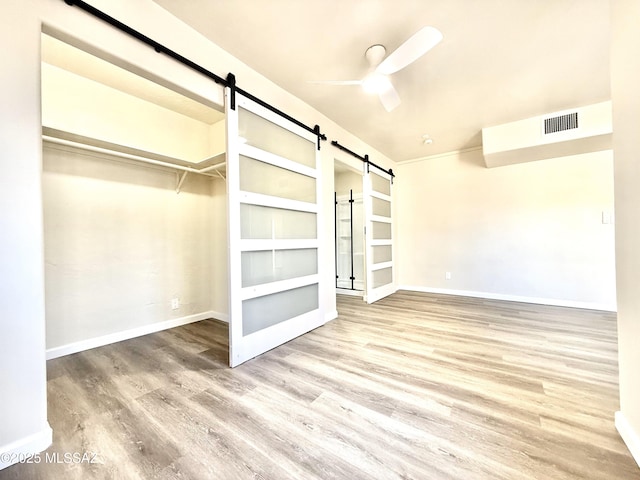 interior space with hardwood / wood-style flooring, a barn door, and ceiling fan