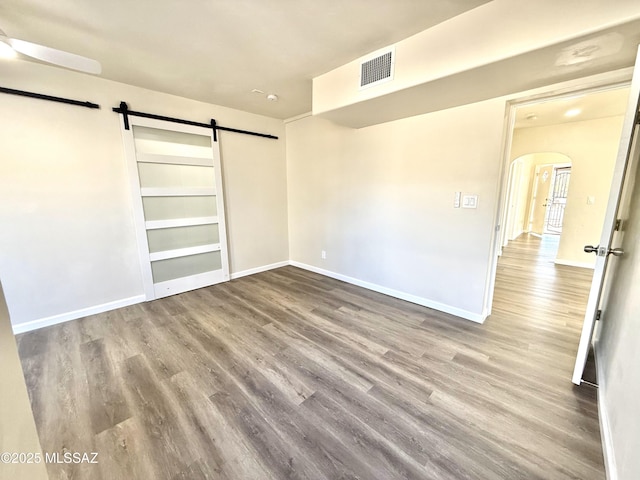 unfurnished bedroom with a barn door, hardwood / wood-style floors, and a closet