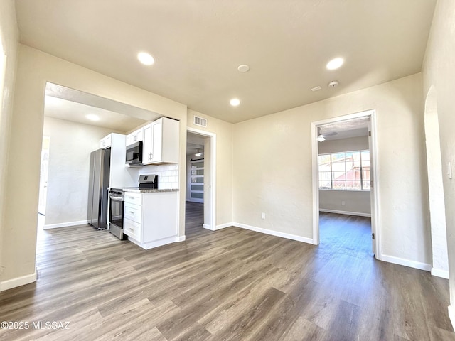 kitchen with white cabinetry, backsplash, hardwood / wood-style flooring, light stone counters, and stainless steel appliances