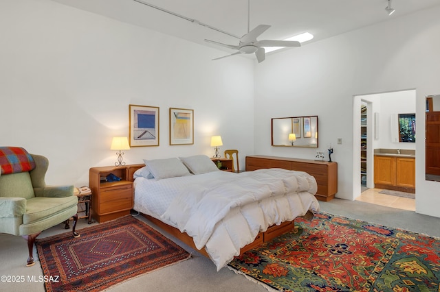 bedroom featuring sink, ensuite bath, ceiling fan, a towering ceiling, and light carpet