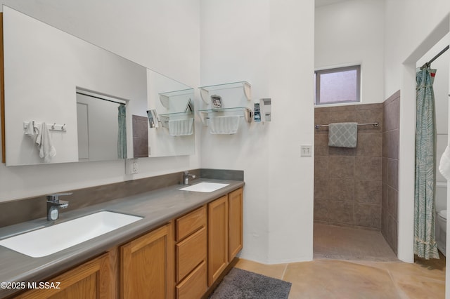 bathroom featuring vanity, tile patterned floors, toilet, and a tile shower