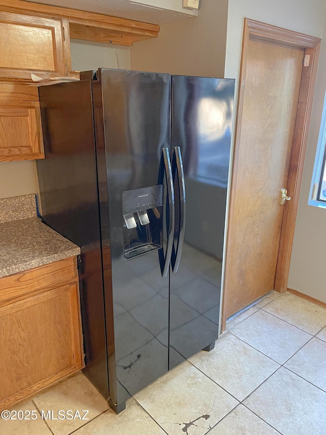 kitchen with light tile patterned flooring and black refrigerator with ice dispenser