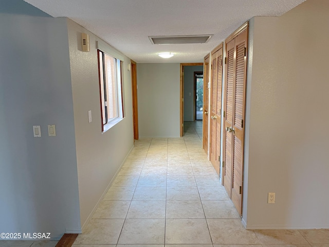 hall featuring light tile patterned flooring and a textured ceiling