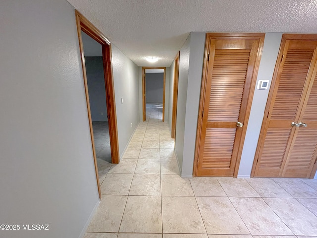 hallway with light tile patterned floors and a textured ceiling