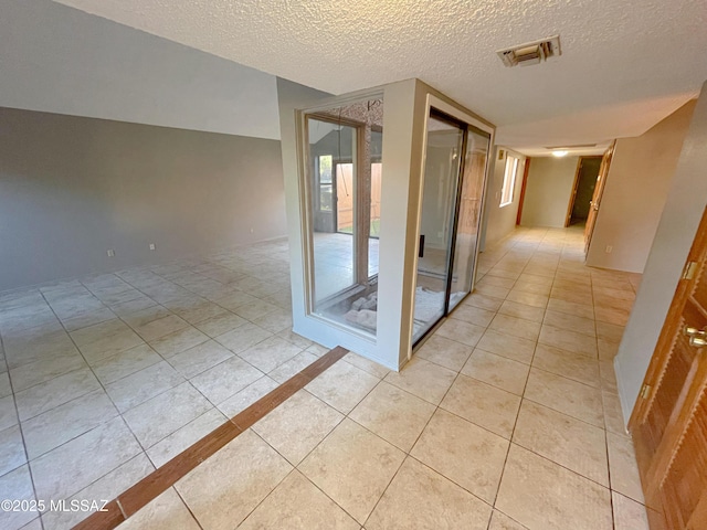 corridor with light tile patterned flooring and a textured ceiling