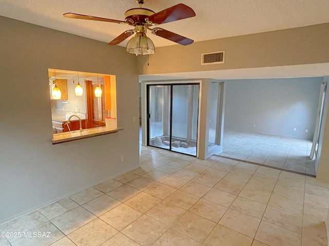 tiled empty room featuring ceiling fan and a textured ceiling