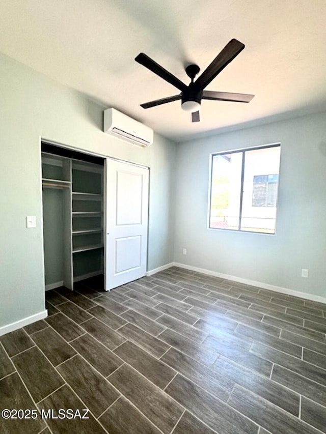 unfurnished bedroom with an AC wall unit, baseboards, a closet, and wood tiled floor