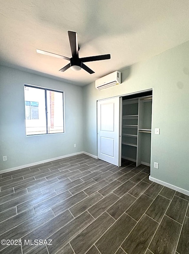 unfurnished bedroom with wood tiled floor, baseboards, a wall unit AC, and a closet
