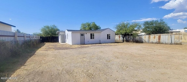 rear view of property featuring a fenced backyard and stucco siding