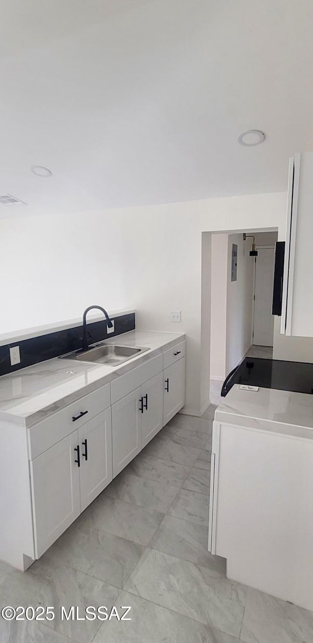 kitchen featuring a sink, washer / clothes dryer, white cabinetry, and marble finish floor