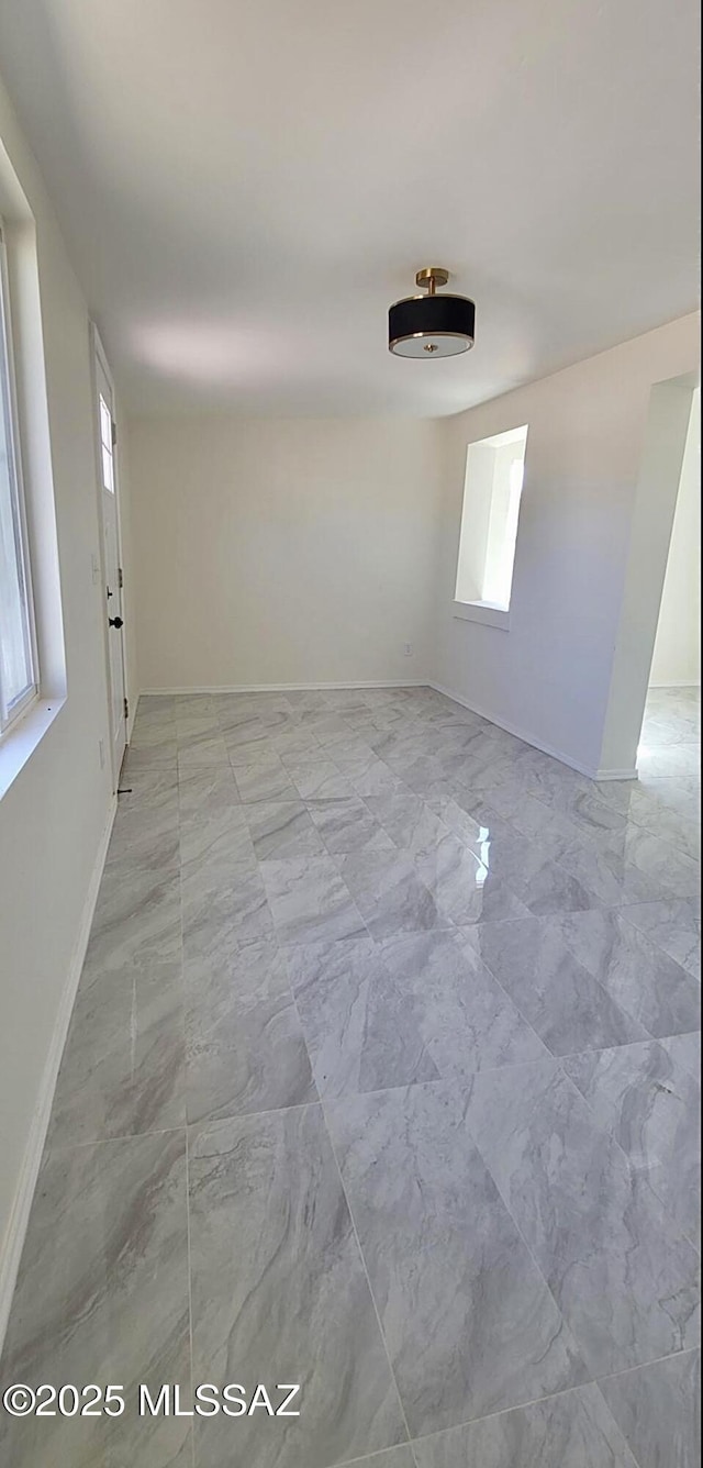 empty room featuring baseboards and marble finish floor