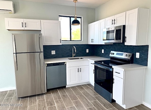 kitchen featuring a wall mounted air conditioner, light countertops, white cabinetry, a sink, and stainless steel appliances