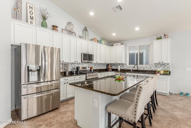 kitchen featuring white cabinetry, appliances with stainless steel finishes, a center island, and a kitchen breakfast bar