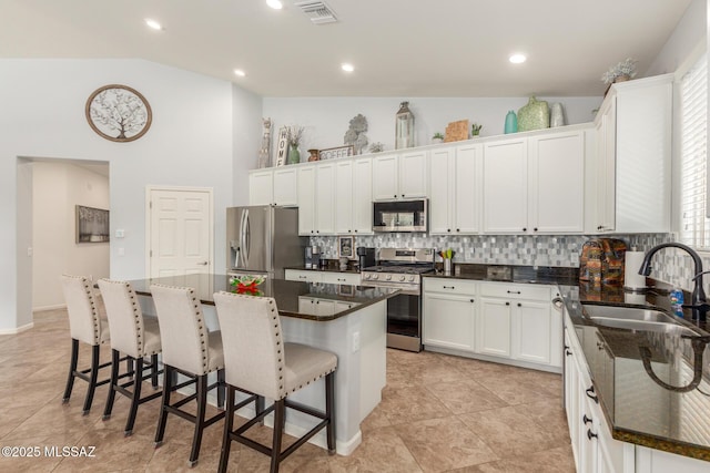 kitchen featuring a breakfast bar, sink, a kitchen island, stainless steel appliances, and white cabinets