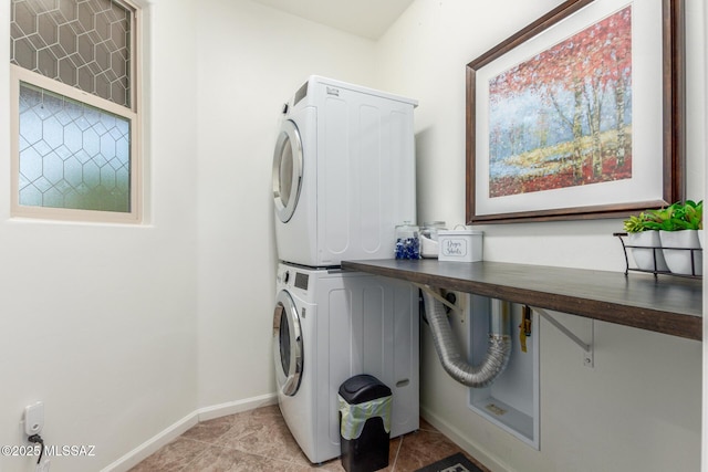 laundry area with stacked washer / drying machine and light tile patterned floors