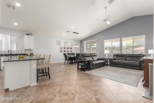 living room featuring vaulted ceiling, ceiling fan, sink, and light tile patterned floors