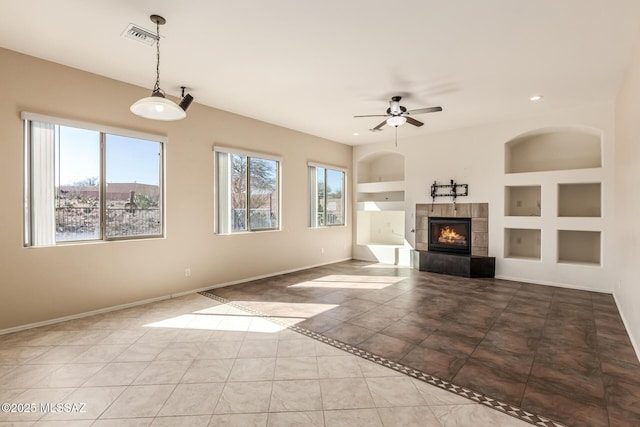 unfurnished living room with light tile patterned flooring, ceiling fan, built in features, and a fireplace