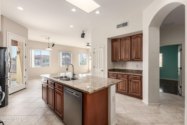 kitchen with pendant lighting, sink, a kitchen island with sink, stainless steel appliances, and light stone countertops