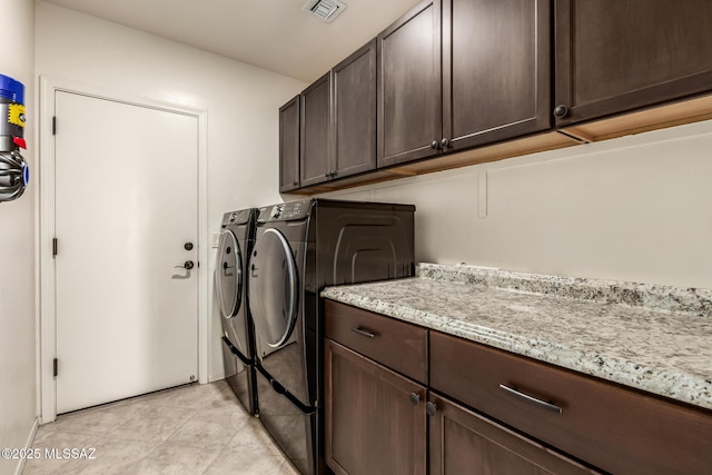 laundry room with cabinets, light tile patterned floors, and independent washer and dryer