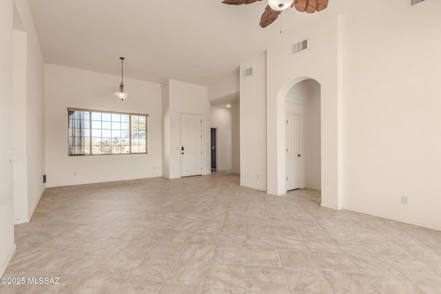 unfurnished room with ceiling fan and a high ceiling