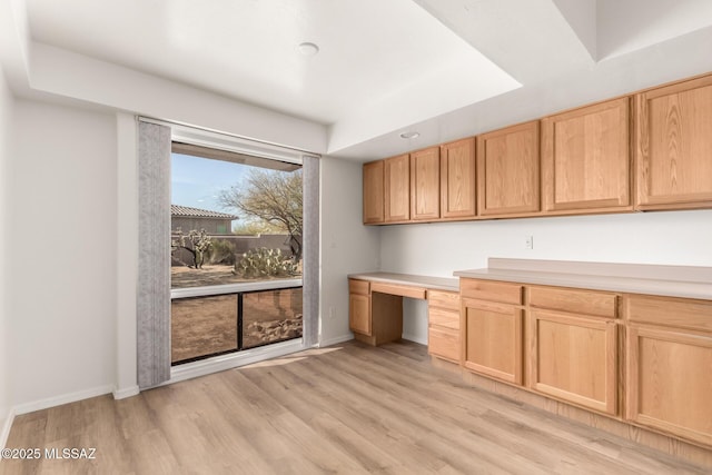 kitchen with built in desk, light hardwood / wood-style flooring, and light brown cabinets