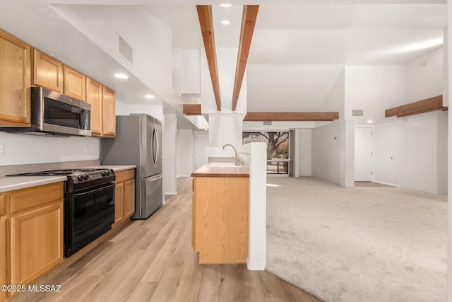 kitchen featuring sink, appliances with stainless steel finishes, an island with sink, light brown cabinetry, and light colored carpet