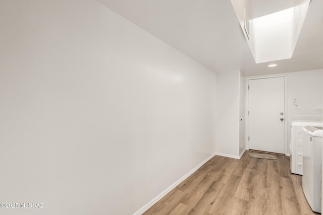 corridor with light hardwood / wood-style floors and washing machine and clothes dryer