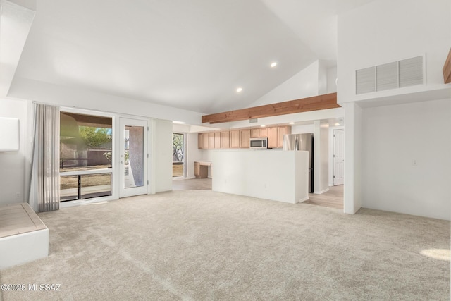 unfurnished living room with high vaulted ceiling and light carpet