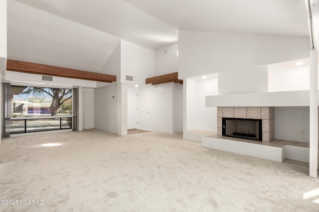 unfurnished living room with light carpet, a tiled fireplace, and high vaulted ceiling