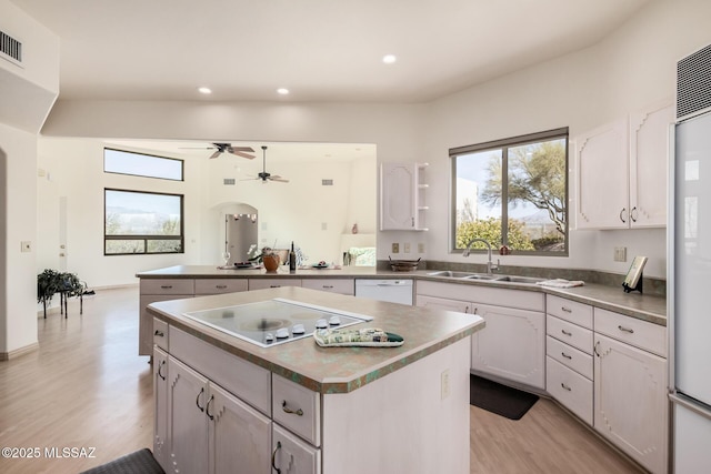 kitchen with sink, white appliances, a center island, and white cabinets