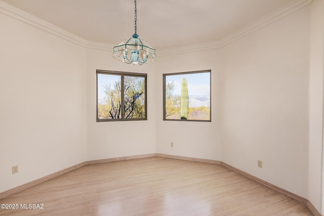 empty room featuring crown molding, a notable chandelier, and light hardwood / wood-style flooring