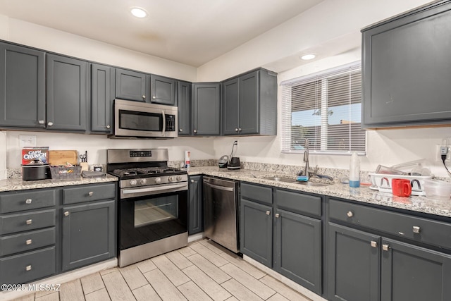 kitchen featuring sink, gray cabinets, stainless steel appliances, and light stone countertops