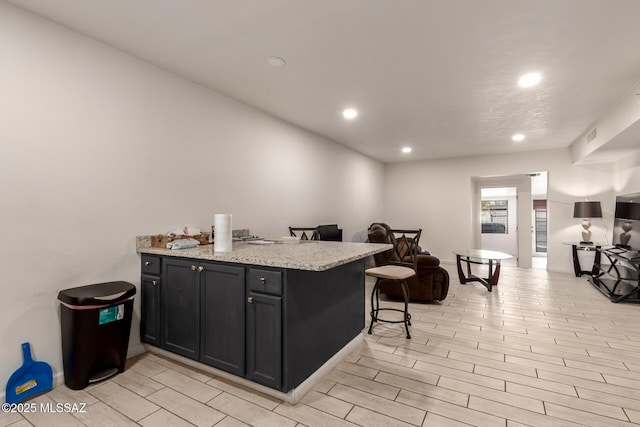 kitchen with light stone countertops, a kitchen breakfast bar, and kitchen peninsula