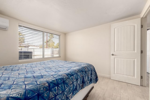 bedroom featuring a wall mounted AC and light wood-type flooring