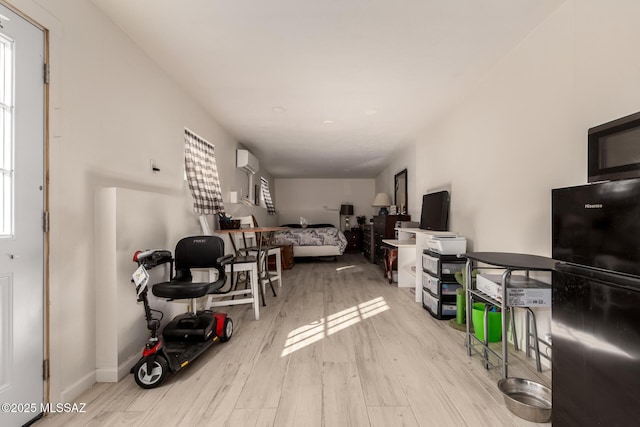 living room featuring plenty of natural light, a wall unit AC, and light hardwood / wood-style floors