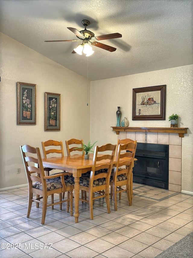 tiled dining space with ceiling fan, lofted ceiling, a fireplace, and a textured ceiling