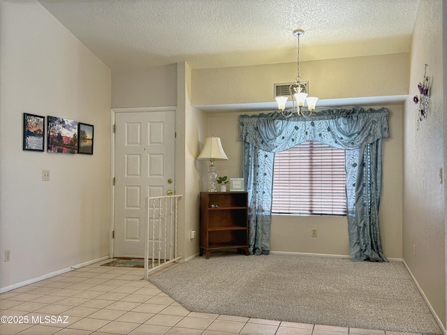 carpeted foyer entrance featuring a textured ceiling and a chandelier