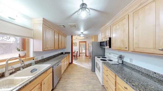 kitchen featuring light brown cabinetry, sink, light wood-type flooring, appliances with stainless steel finishes, and dark stone counters