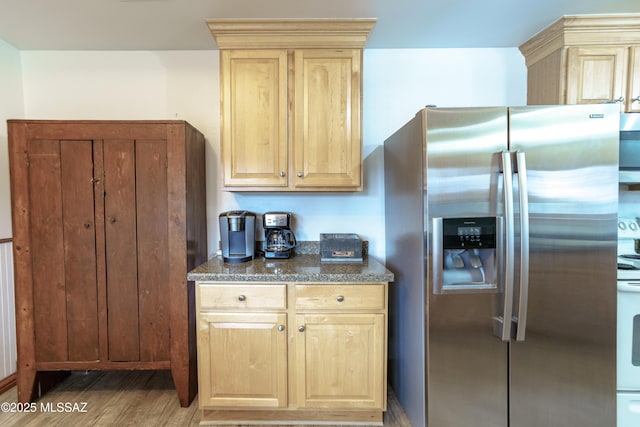 kitchen featuring light wood-style floors, dark stone counters, stainless steel fridge with ice dispenser, light brown cabinetry, and electric stove