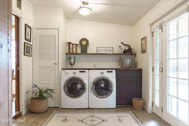 laundry room with washer and clothes dryer and light hardwood / wood-style floors