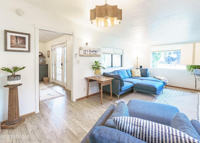 living room with light wood finished floors, baseboards, and vaulted ceiling