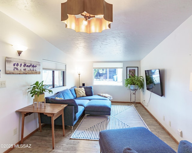 living room featuring hardwood / wood-style flooring, lofted ceiling, and a textured ceiling