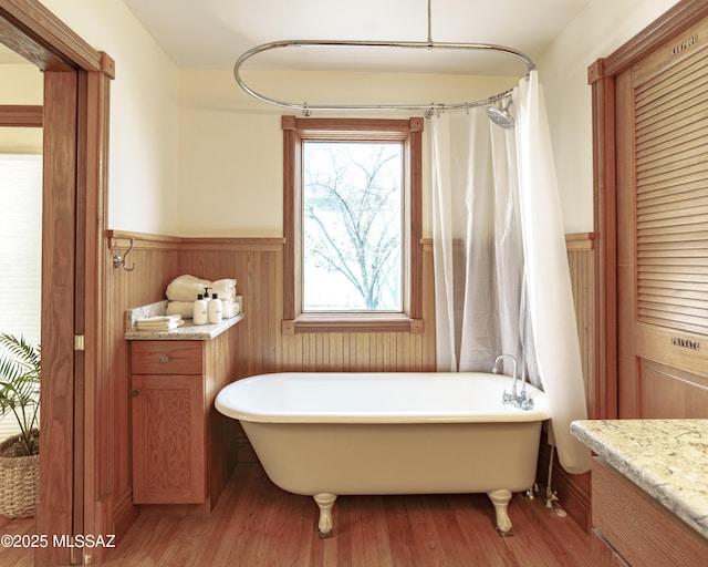 bathroom featuring a freestanding tub, wood finished floors, and wainscoting